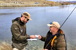 WFR2526.03 F&G Officer Jase checks a compliant, happy angler.